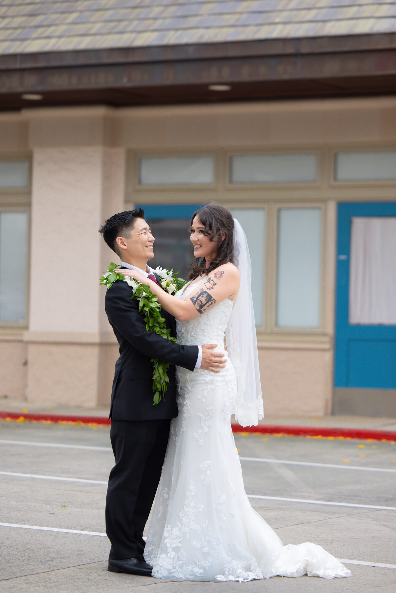 Bride and groom embrace during their first look, groom wearing a maile lei, at an Oahu wedding