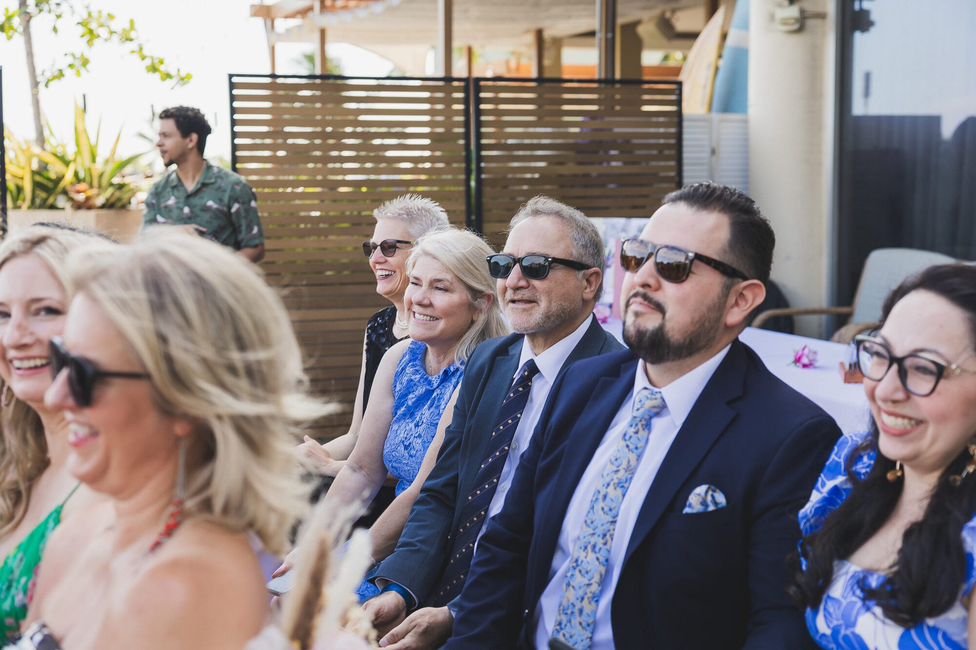 Smiling guests in aloha attire at an outdoor Oahu wedding ceremony