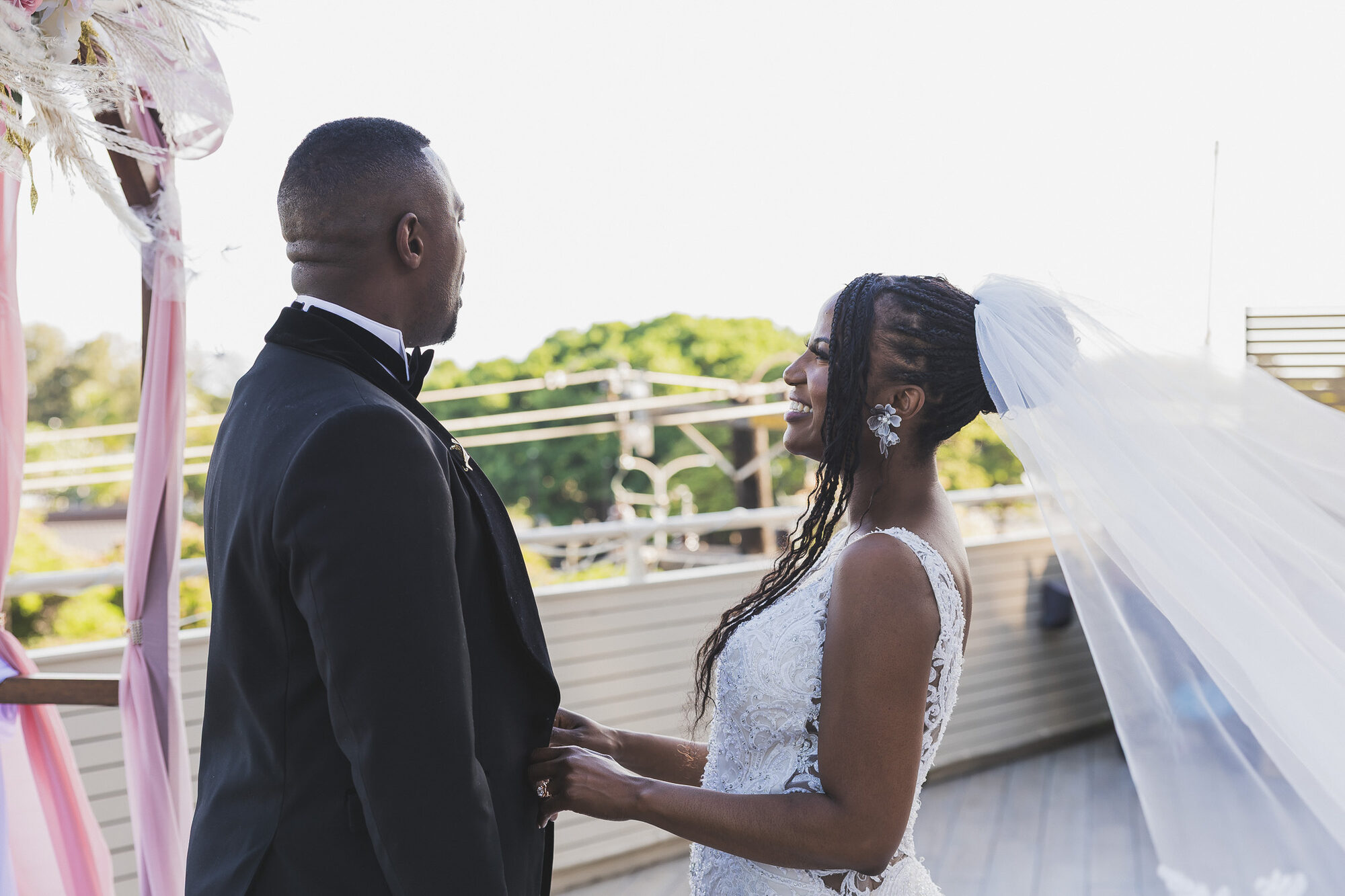 Bride and groom share a tender moment at a rooftop Oahu wedding, veil flowing in the breeze