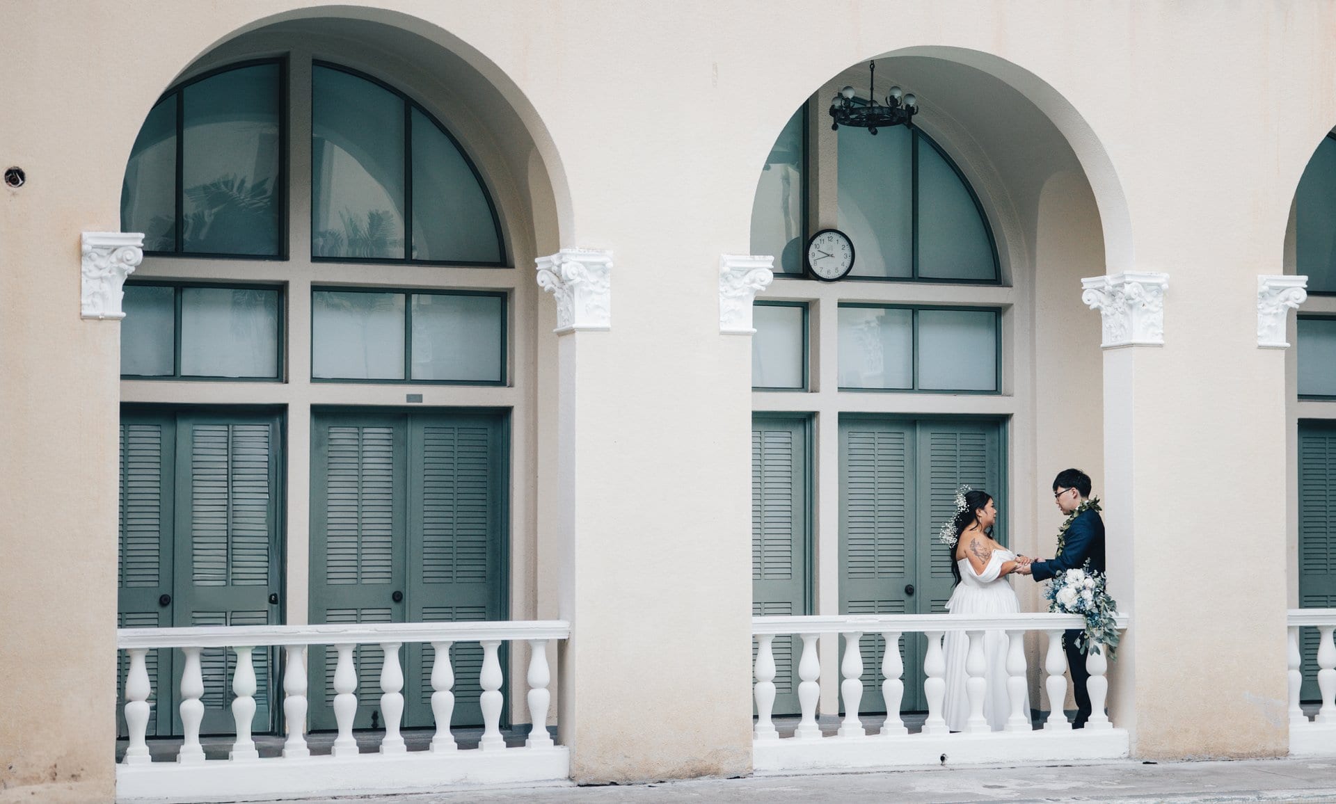 Bride and groom embrace on balcony at historic Honolulu wedding venue